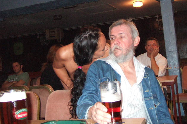 stripper with head bent down next to oldish man with grey beard